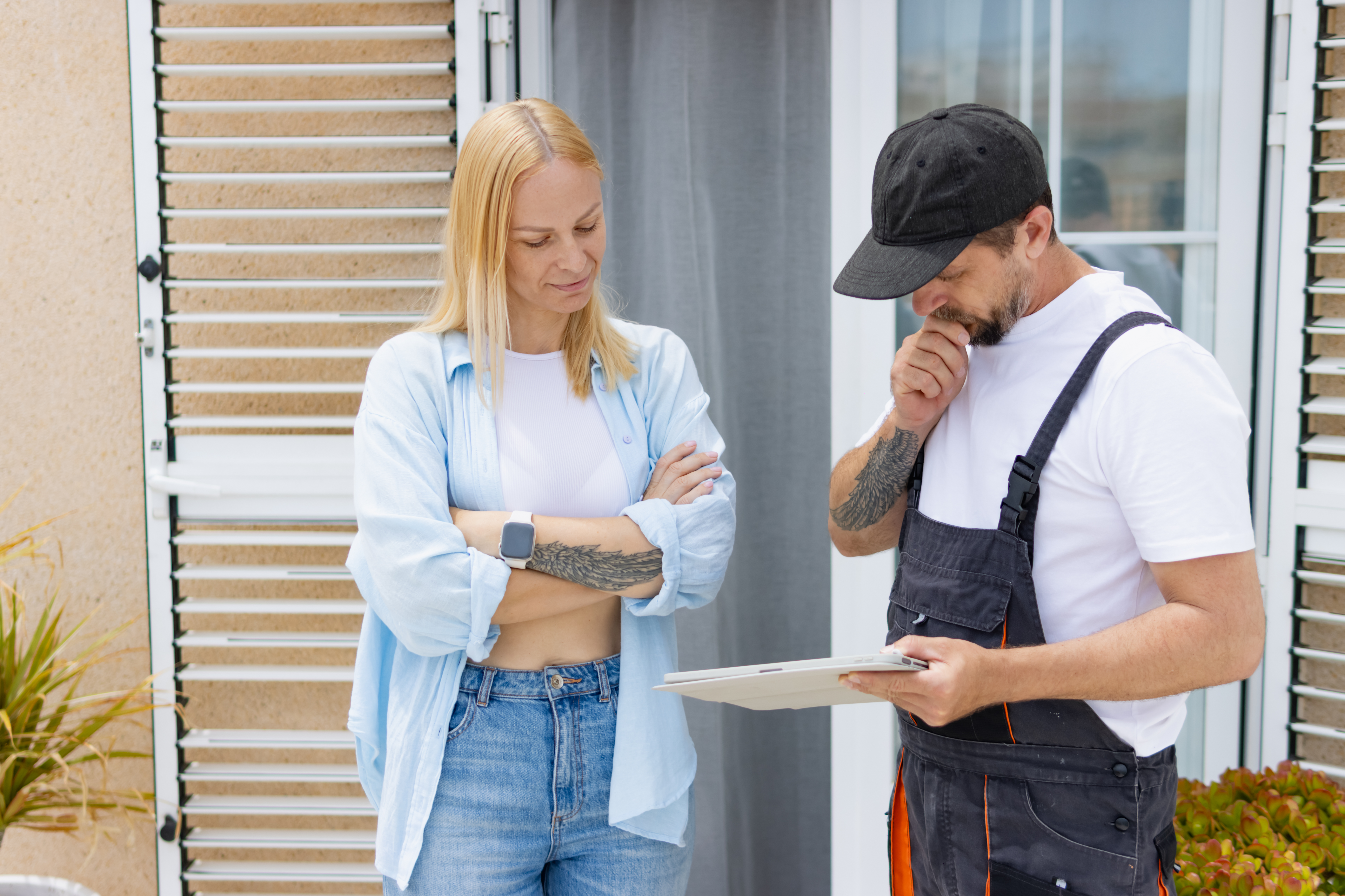 Homeowner looking skeptical and evaluating a repair proposal from a professional handyman, discussing project scope, pricing, and scheduling for home renovation or service work